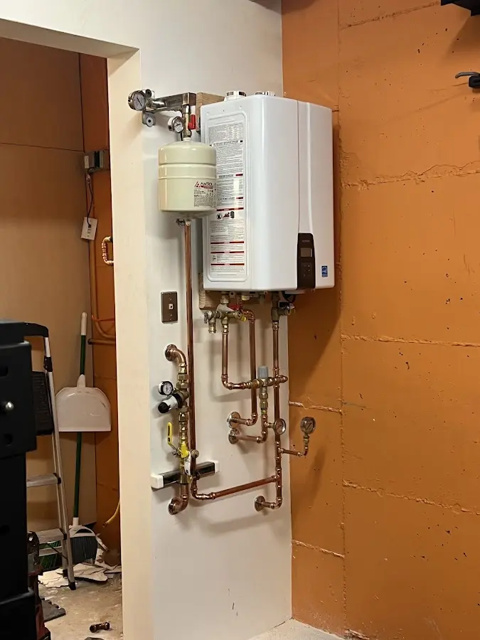 Plumbing technician inspecting water heater connections in Five Corners